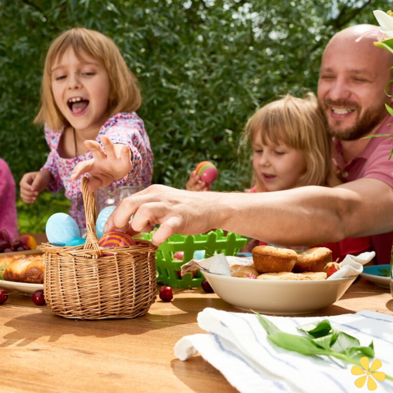 Children joyfully reaching for colorful Easter eggs in a sunny outdoor setting.