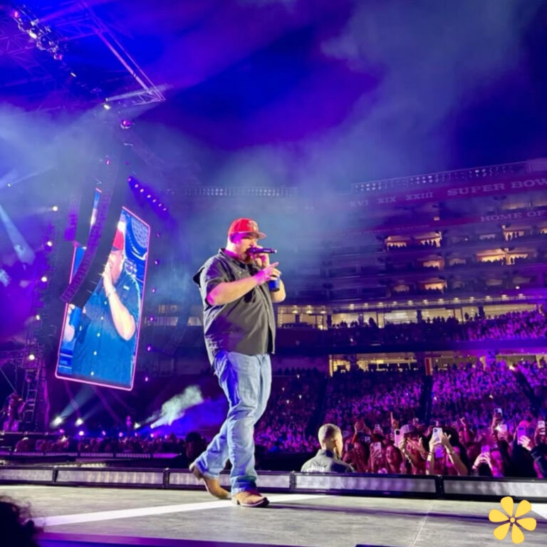 A performer on stage in a lively concert atmosphere, wearing a red cap and holding a microphone.