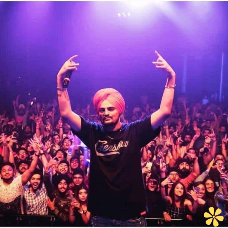 A lively crowd enjoys a performance, with a singer in a turban posing energetically on stage.