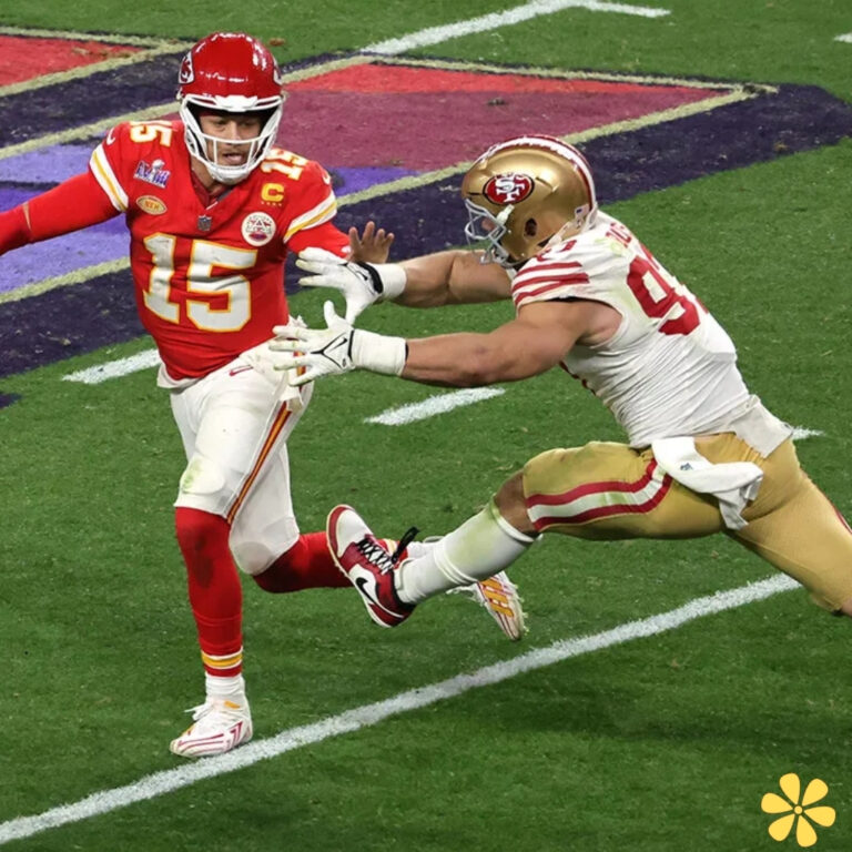 A football player in red dodges a tackle from an opponent in white during an intense game.