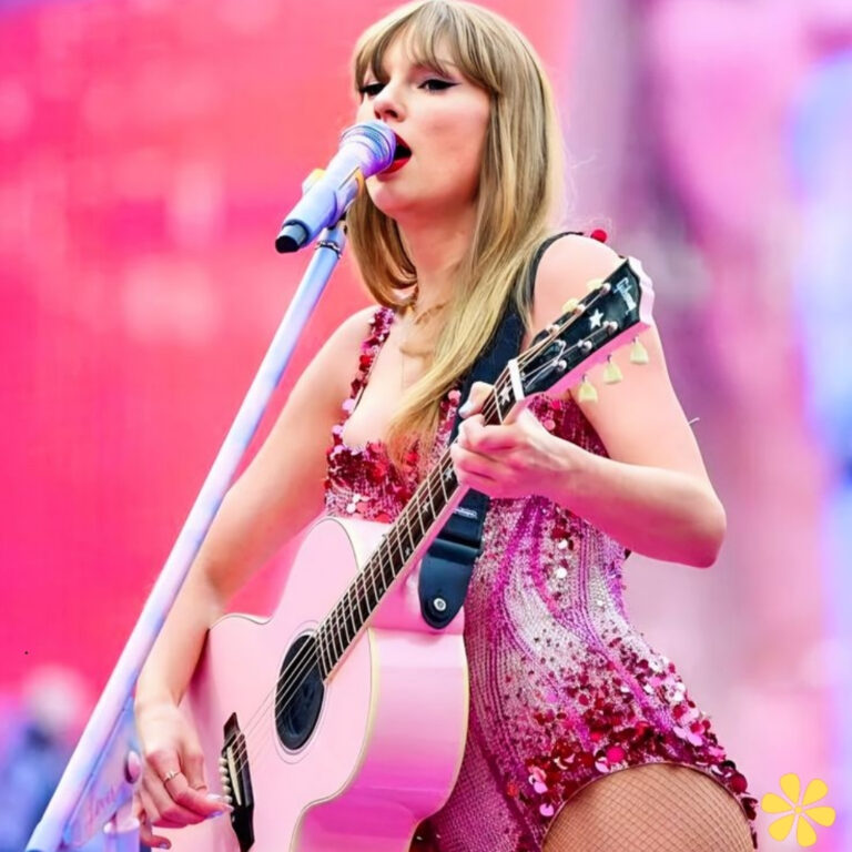 Taylor Swift strums a pink guitar, shining in a sparkling outfit, while singing passionately.