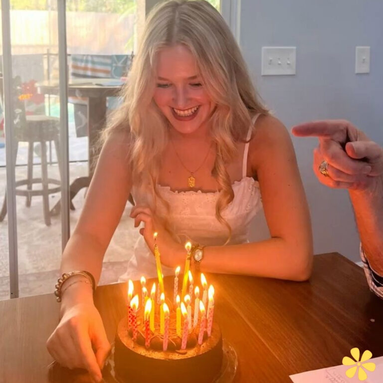 Young woman joyfully lights birthday candles on a cake, surrounded by a festive atmosphere.