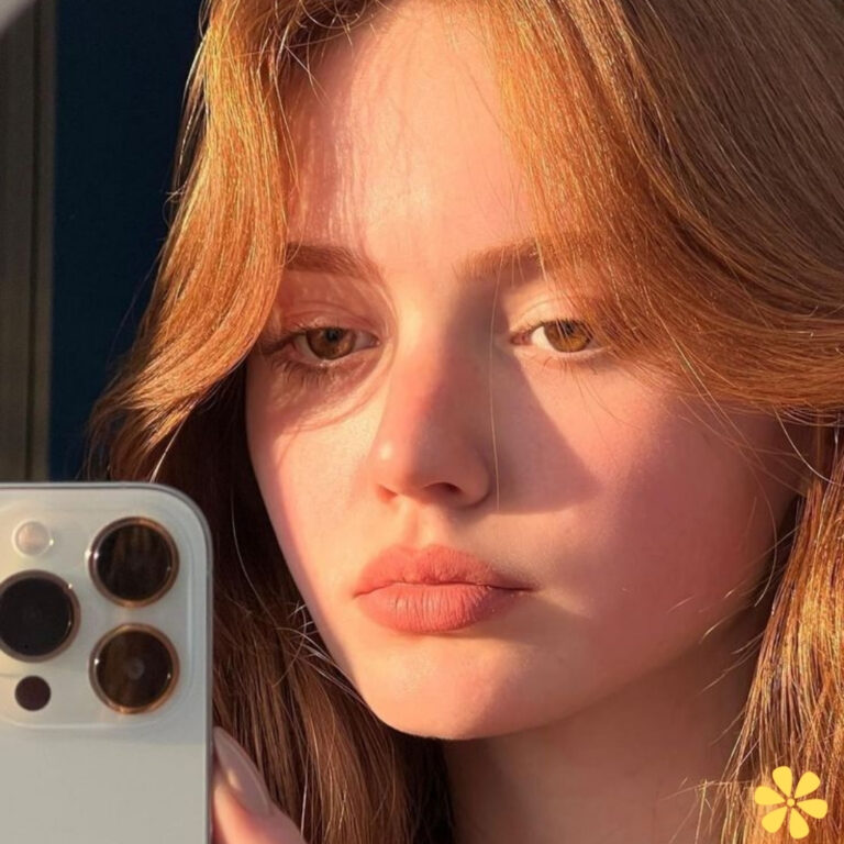 Close-up of a young woman with warm light reflecting on her face, showcasing her soft features and golden hair.