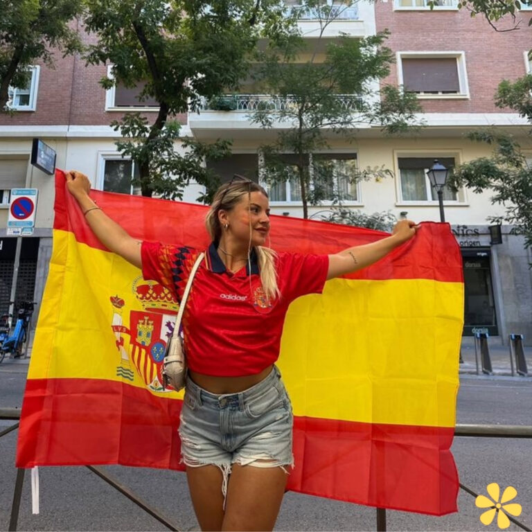 Young woman in a red shirt proudly holding the Spanish flag.
