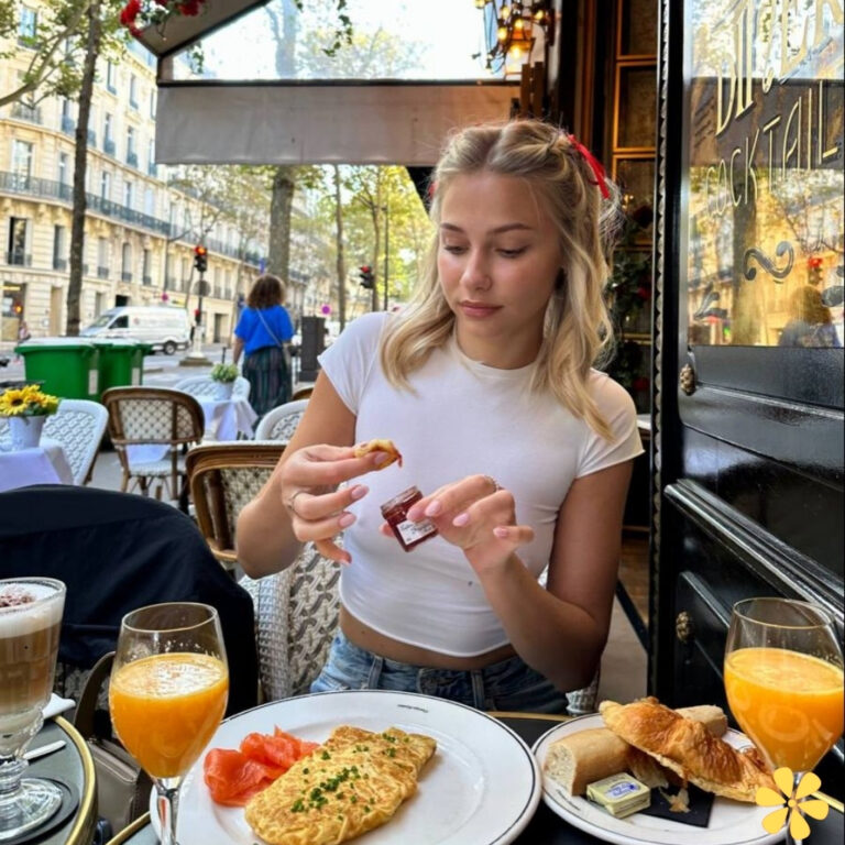 Young woman enjoying breakfast with an omelet, croissants, and drinks at a café.