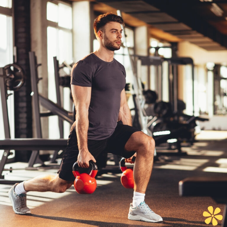 Man lunges in gym, holding kettlebells, focused and determined.