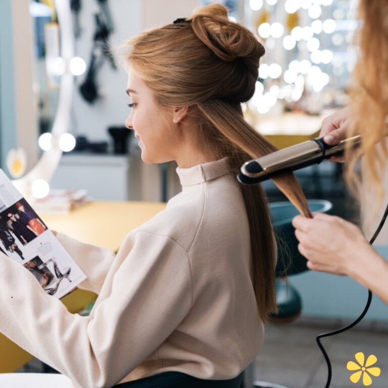 Woman getting her hair styled while reading a magazine in a salon.