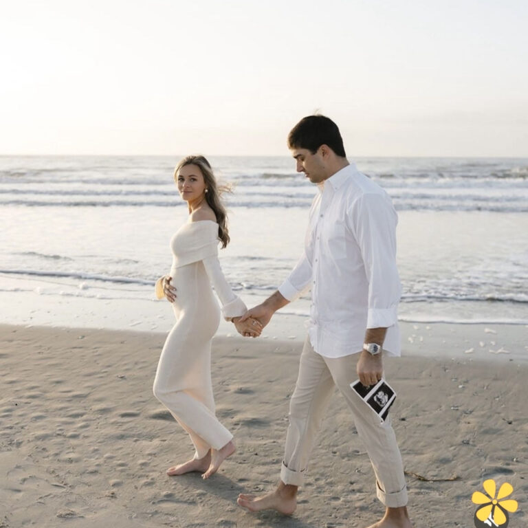 Couple walking hand in hand on the beach at sunset, woman in white dress, man in white shirt.