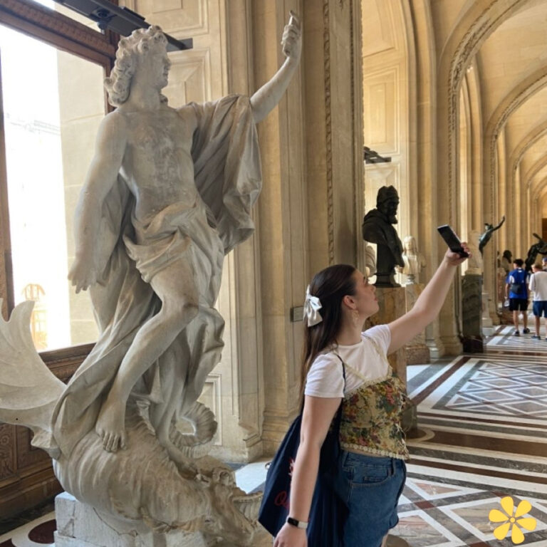 A woman poses for a selfie in front of a statue, exuding joy and excitement.