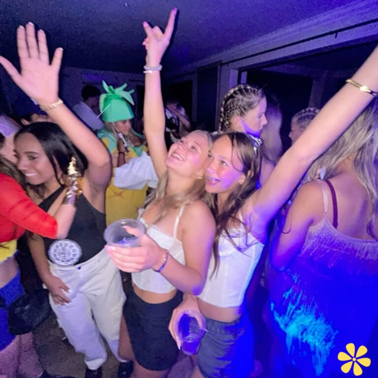 Group of friends enjoying a lively party, hands raised, smiles all around.