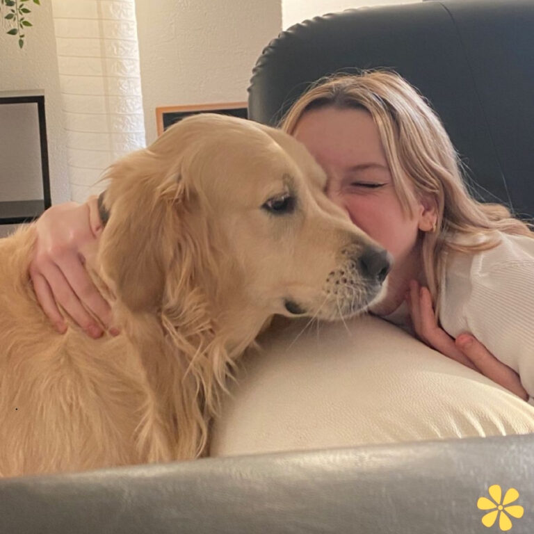 A golden retriever and a girl share a warm moment, both smiling and enjoying each other's company.