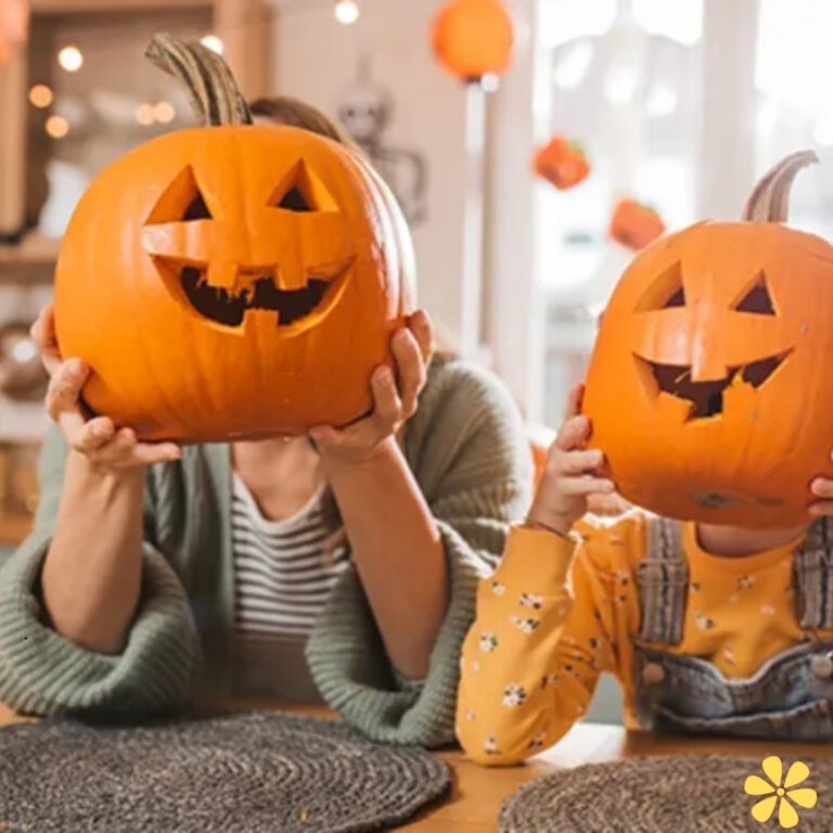 Two people hold carved pumpkins, grinning happily with playful designs, in a cozy indoor space.