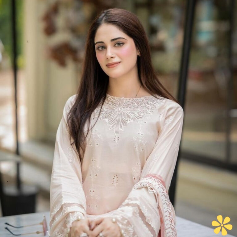 A young woman with long hair poses elegantly in a soft pink outfit, smiling gently at the camera.