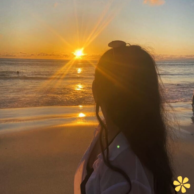 Silhouette of a woman watching a sunset at the beach, sun rays shining beautifully.