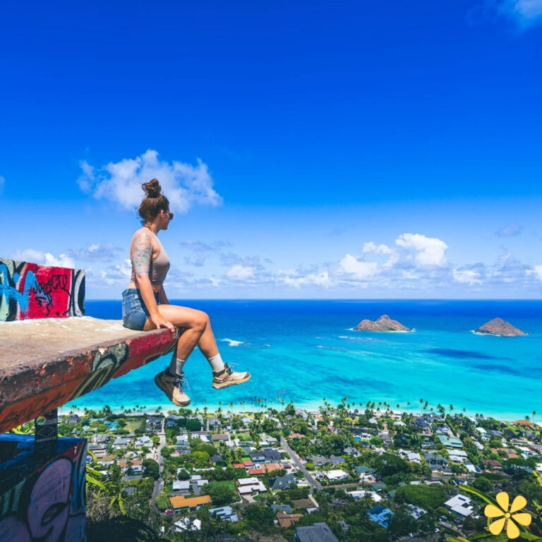 Woman sitting on a ledge overlooking blue ocean and islands, with colorful graffiti around her.