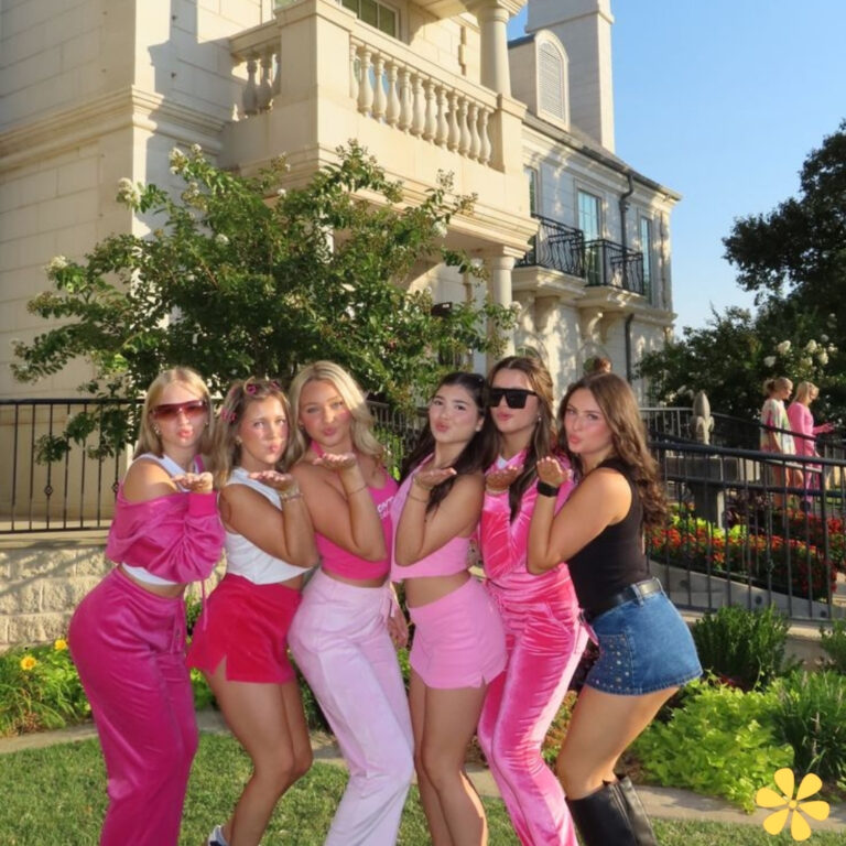 Six friends pose playfully in matching pink outfits, making funny faces with puckered lips.