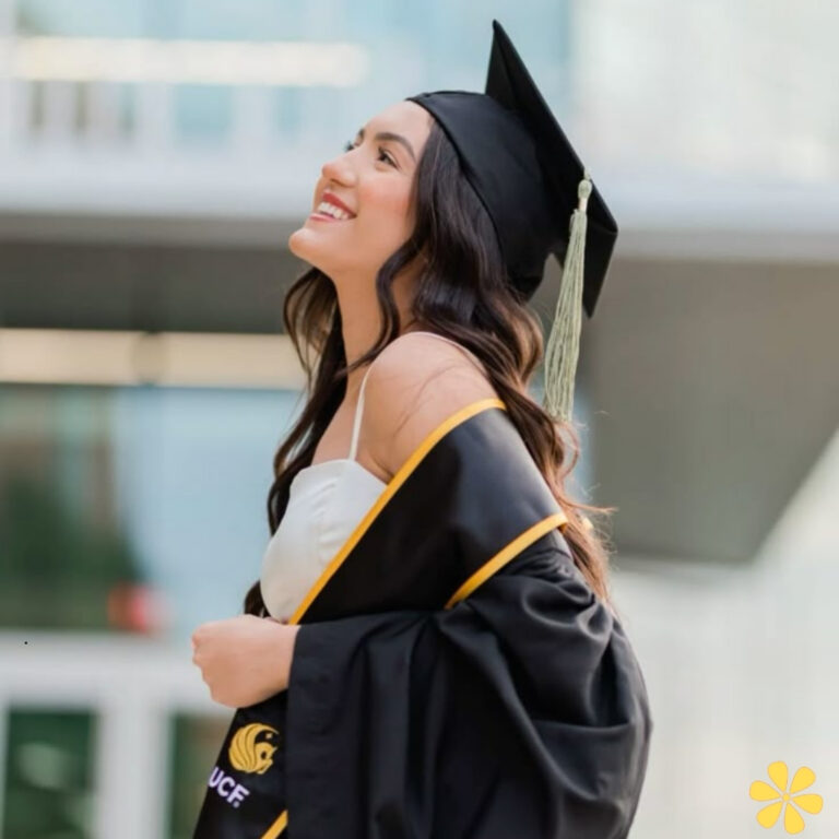Graduating student smiles in cap and gown, celebrating achievement.