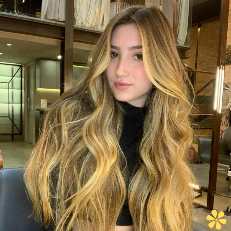 Young woman with long, wavy blonde hair in a salon setting.