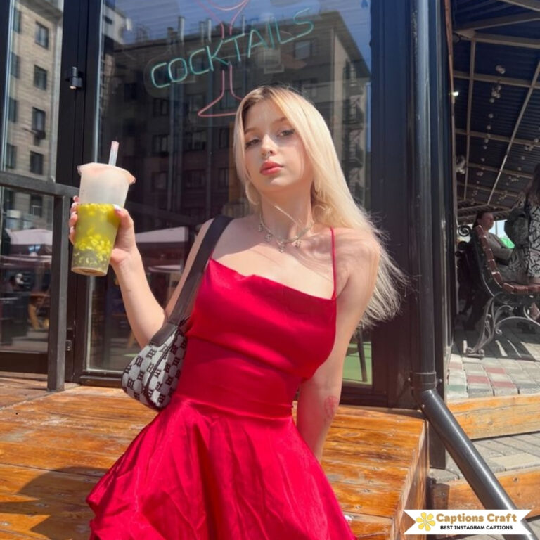 Young woman in a red dress holding a drink, standing outside a bar.