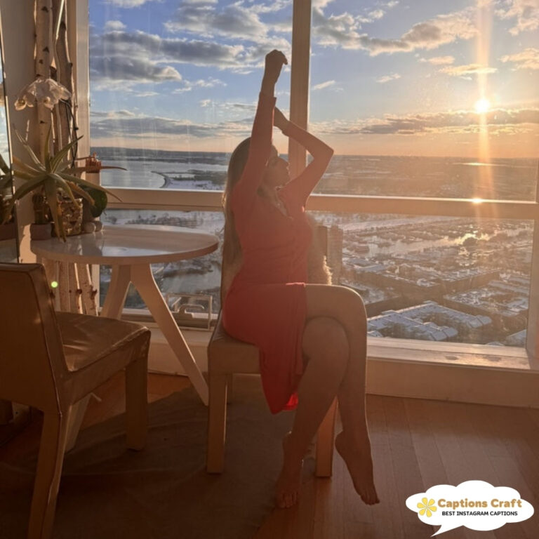 Woman in a red dress stretches by a window with a scenic view.