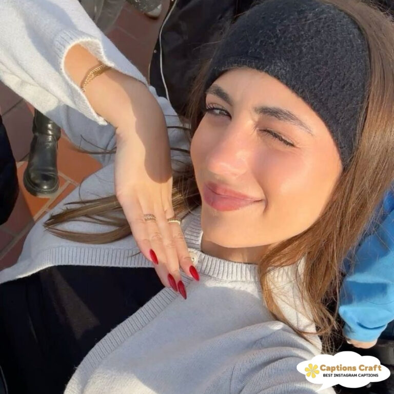 Woman winks, showcasing long red nails, wearing a headband and a cozy sweater.