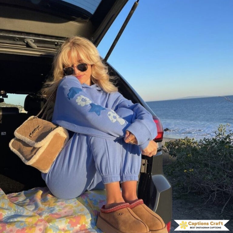 Woman in blue outfit sits in car trunk by beach at sunset.